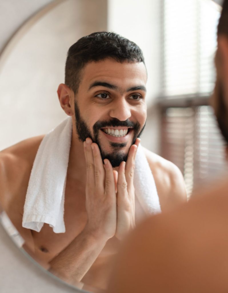 man-looking-in-the-mirror-with-new-dental-implant