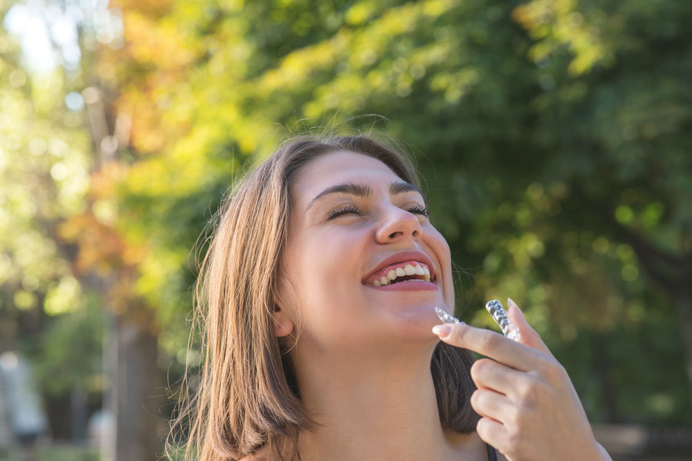 A lifestyle image of a woman wearing Invisalign. Smile Concepts uses this to show invisibility. The visual proves the claim. The theme is discreet wear. The alt text emphasizes that patients can wear Invisalign confidently in their daily lives, as the aligners are virtually invisible, allowing them to straighten their teeth without anyone knowing.